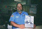 Beaming Sheriff Ron Moore holds photograph of J. C. Redfield