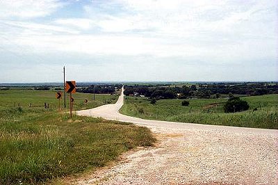 Yellow gravel road turning toward the horizon
