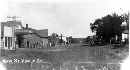 Broad, unpaved street with low town buildings on either side